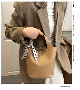 Detail of camel bucket bag in lychee leather featuring a polka dot scarf handle accent