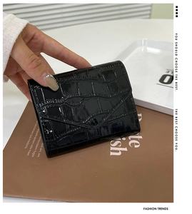 Detail of black faux crocodile skin envelope wallet held by hand in a stylish setting