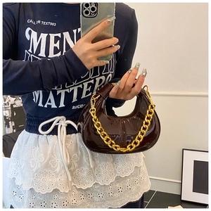 Close-up of a dark brown patent leather dumpling bag with chunky gold chain detail