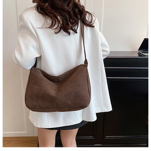 Detailed back view of a large dark brown suede hobo bag worn by a model in casual style