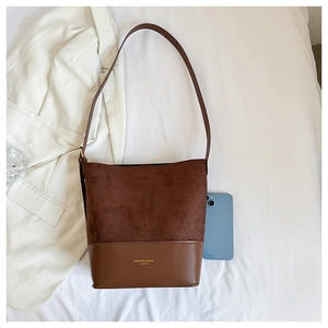 Detail of two-tone brown leather shoulder bag with gold lettering and contrast texture