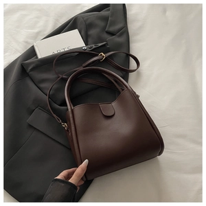 Deep brown bucket bag with smooth PU leather texture and adjustable strap on a grey suit
