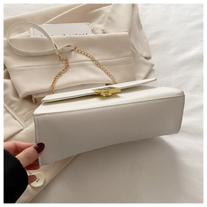 Detail of white leather crossbody bag with golden chain strap and metallic press buckle