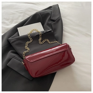 Détail du sac baguette en cuir verni bordeaux avec bandoulière chaîne dorée
