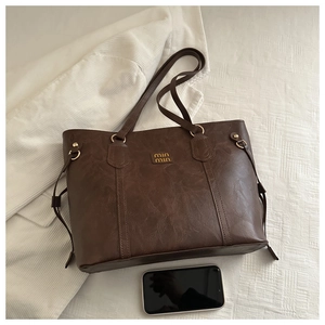 Detail of dark brown leather tote bag with vintage texture and smartphone size reference
