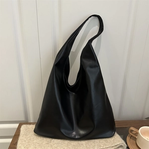 Minimalist black faux leather hobo shoulder bag with a soft drape on a wooden table