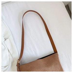 Detail view of brown suede texture and golden metal hardware buckle on the shoulder bag