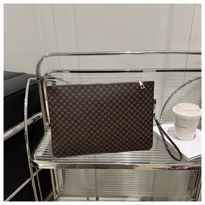 Detail of dark brown envelope clutch bag with polka dots and gold zipper closure