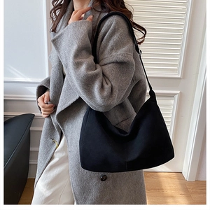 Side view of a black matte shoulder bag on a model featuring a simple crescent shape