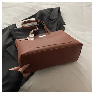 Detail of brown leather tote bag with silver bar and vintage printed silk scarf handle