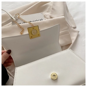 Close-up of a white leather crossbody bag with a golden square magnetic buckle and chain