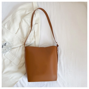 Detail of warm brown leather bucket bag with adjustable strap and smooth texture