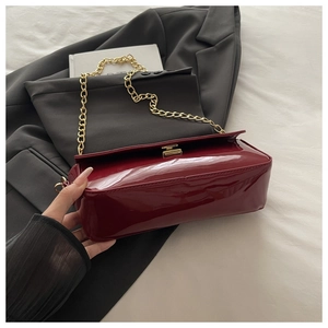 Détail du mini sac en cuir verni rouge avec bandoulière chaîne et fermoir doré chic