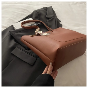 Close-up of brown leather tote bag with stylish floral silk scarf wrapped around handle