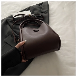 Detailed side view of dark brown faux leather bucket bag with rounded texture and strap