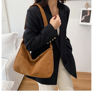 Dettaglio borsa hobo in pelle scamosciata caramello con blazer nero e pantaloni beige eleganti
