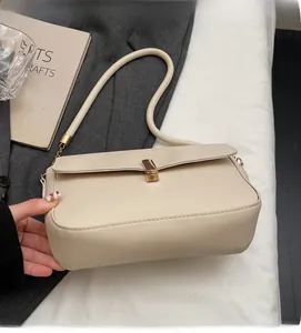Close-up of creamy white faux leather underarm bag with elegant gold metal buckle detail