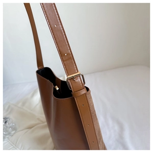 Close-up of adjustable strap and gold buckle on a brown minimalist shoulder bag