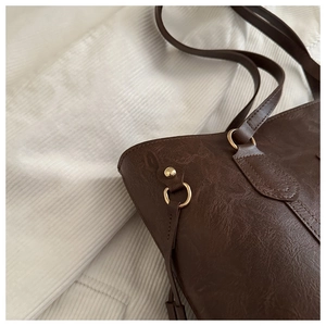 Close-up of deep brown tote bag featuring vintage pebble texture and gold hardware detail