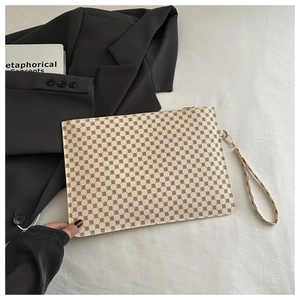 Dettaglio della borsa a mano color crema con motivi geometrici rossi e zip dorata