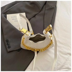 Detail of white moon bag with gold chunky chain and metallic buckle on a grey blazer