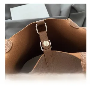 Detail view of brown pebbled leather bucket bag showing silver hardware and stitching