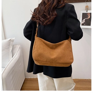 Brown faux suede half-moon tote bag with minimalist stitching shown on a model