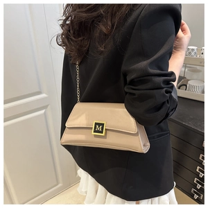 Detail of a beige leather crossbody bag with a gold metal M-buckle and chain strap