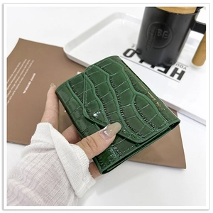 Detailed macro view of dark green crocodile texture on a polished leather tri-fold wallet