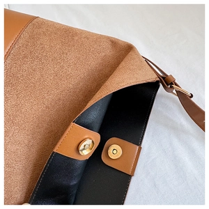 Detail view of the brown suede bag showing golden magnetic buckles and black leather interior