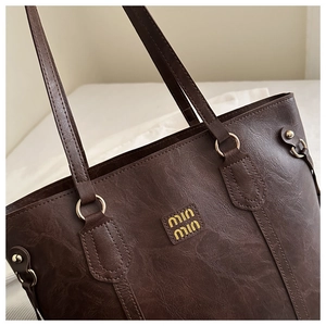 Detail of dark brown faux leather tote with vintage texture and gold ring hardware