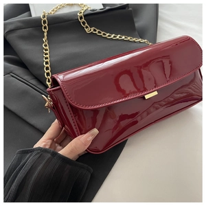 Détail d'un sac en cuir verni bordeaux avec chaîne dorée et boucle métallique élégante