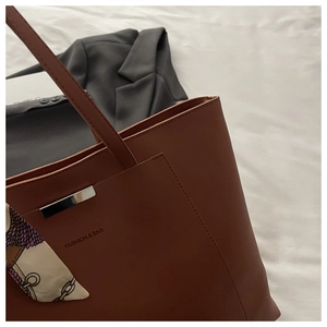 Close-up of brown tote bag featuring silver metal detail and decorative printed silk scarf