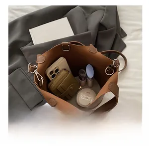 Top-down view of a brown bucket bag showing spacious interior with phone and makeup items