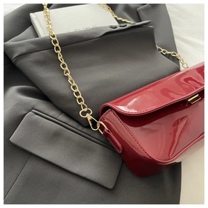 Détail d'un sac à bandoulière en cuir verni rouge brillant avec une chaîne dorée chic