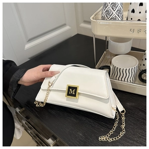 Detail of white leather crossbody bag with golden chain and M-logo metal buckle clasp