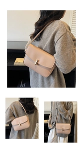 Detailed close-up of beige leather shoulder bag featuring gold cylindrical metal lock