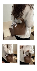 Detail of brown litchi grain leather bucket bag with polka dot scarf and strap