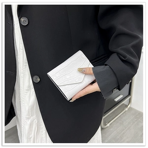 Close-up of white crocodile pattern texture on a glossy minimalist women's mini handbag