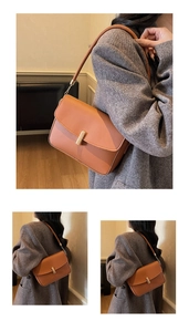 Detail of tan leather shoulder bag with golden cylinder clasp and chain strap links