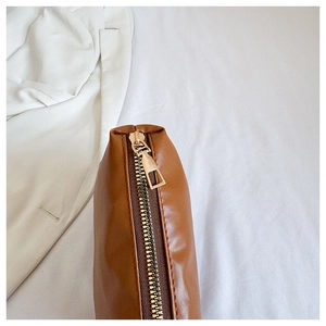 Detailed close-up of premium brown PU leather bag with smooth golden metal zipper puller