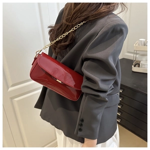 Détail du sac à bandoulière en cuir verni bordeaux avec chaîne dorée et fermoir métal