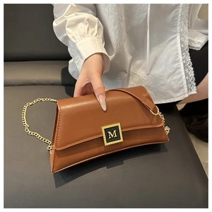 Detail of caramel leather shoulder bag with gold M-logo buckle and chain strap