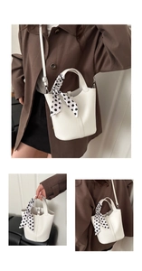 Detailed view of a white pebble leather bucket bag with a stylish polka dot scarf accessory