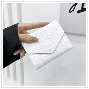 Detailed view of white crocodile pattern envelope clutch bag held by a person