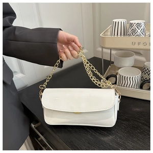 Détail du sac à bandoulière en cuir verni blanc avec chaîne dorée et finition brillante chic