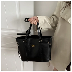 Detailed shot of the black tote bag showing gold logo and premium leather texture
