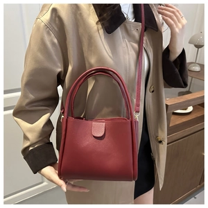 Crossbody view of dark red square bag with a long strap on a stylish trench coat