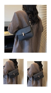 Detail of black leather underarm bag with metal buckle and shoulder strap chain details