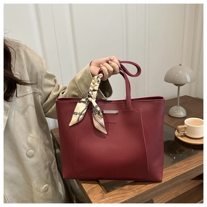 Detail of burgundy tote bag with silver bar and elegant silk scarf accessory